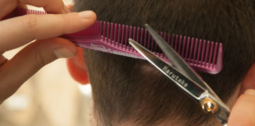 Homem cortando cabelo com tesoura e régua